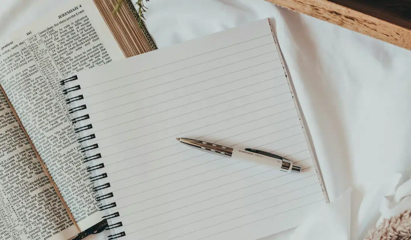 a picture of a notebook with a pen and a bible in the background